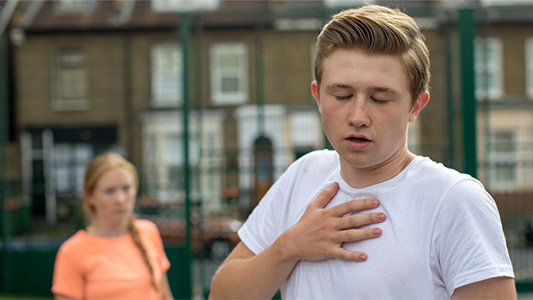 Josh holds his chest as he has difficult breathing