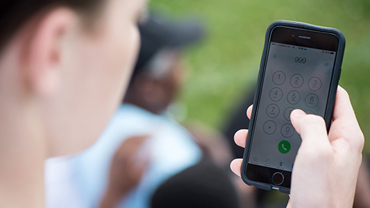 A young person calling 999 on their mobile phone. Person ifanc yn ffonio 999 ar ei ffôn symudol. 