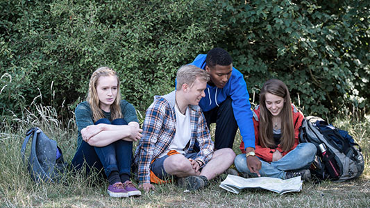 Michael and his friends are looking at a map while on a hike. Allanah looks worried. Mae Michael a'i ffrindiau yn edrych ar fap tra ar heic. Mae Allanah yn edrych yn bryderus. 