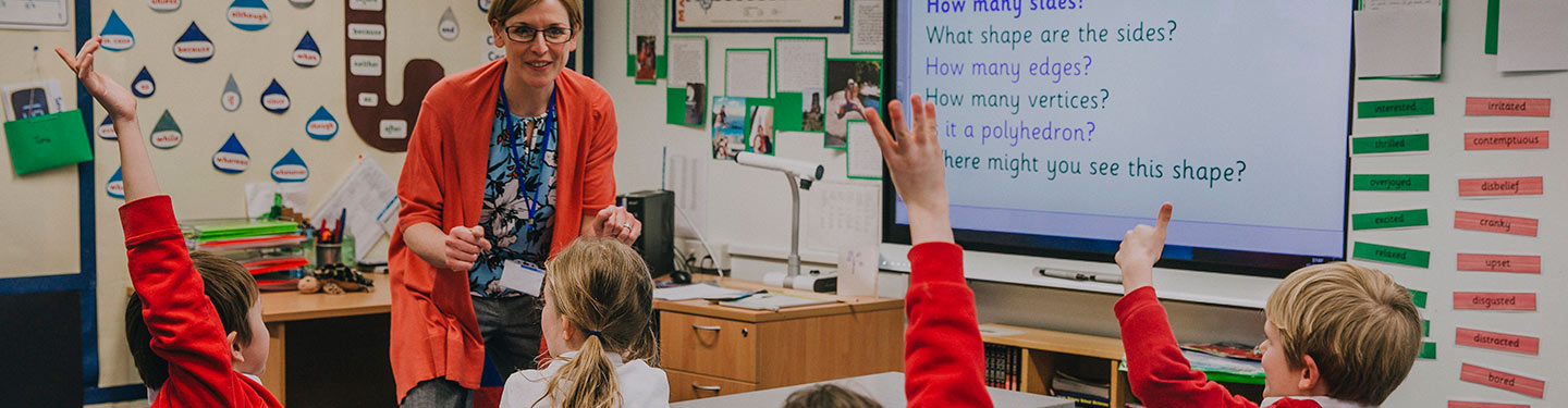 School children raising their hands to answer a teacher's question