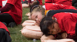 Sophie and other schoolchildren are practising checking for breaths on a manikin